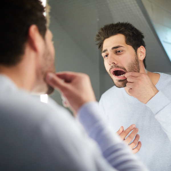 Young man checking tooth in bathroom