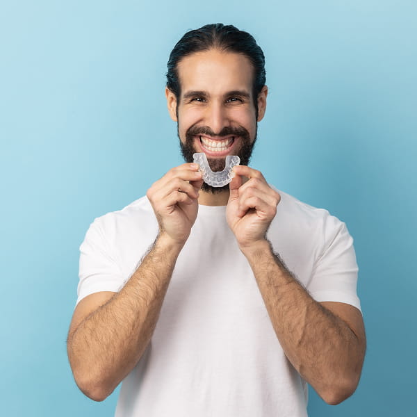 A man is smiling while holding protective mouthguard