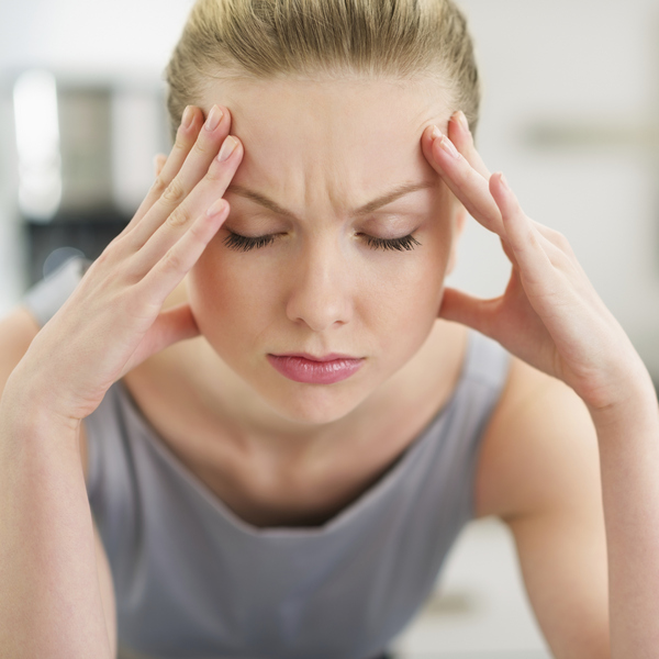 A woman is holding her hands near her face in pain