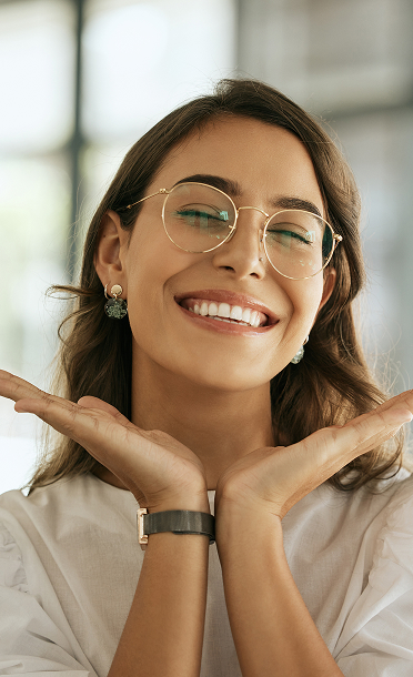 A woman is smiling with two hands near her face
