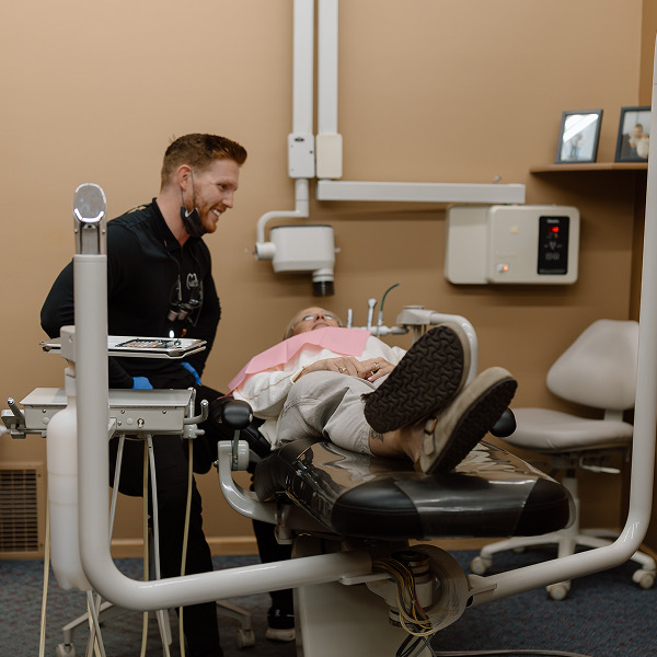 Dentist is looking at patient comfortably lying in the dental chair