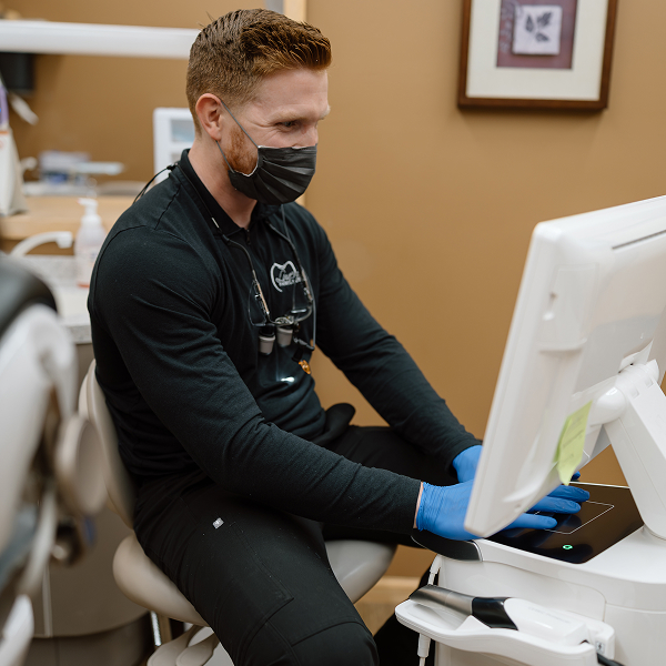 Local dentist is looking at monitor with a smile on his face
