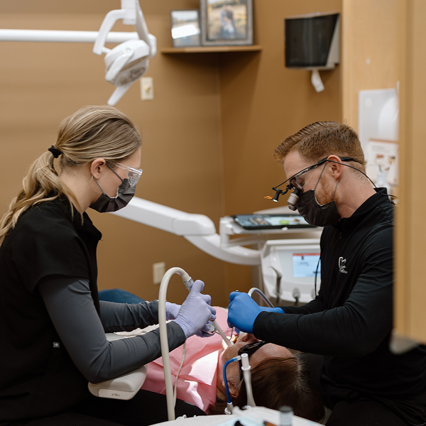 Local dentist with his assistant performing dental procedure on a patient in a dental chair